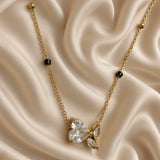 Full view of gold-tone necklace with black bead accents and heart butterfly pendant on cream satin