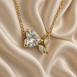 Close-up of clear heart-shaped stone and butterfly detail on a gold-tone necklace
