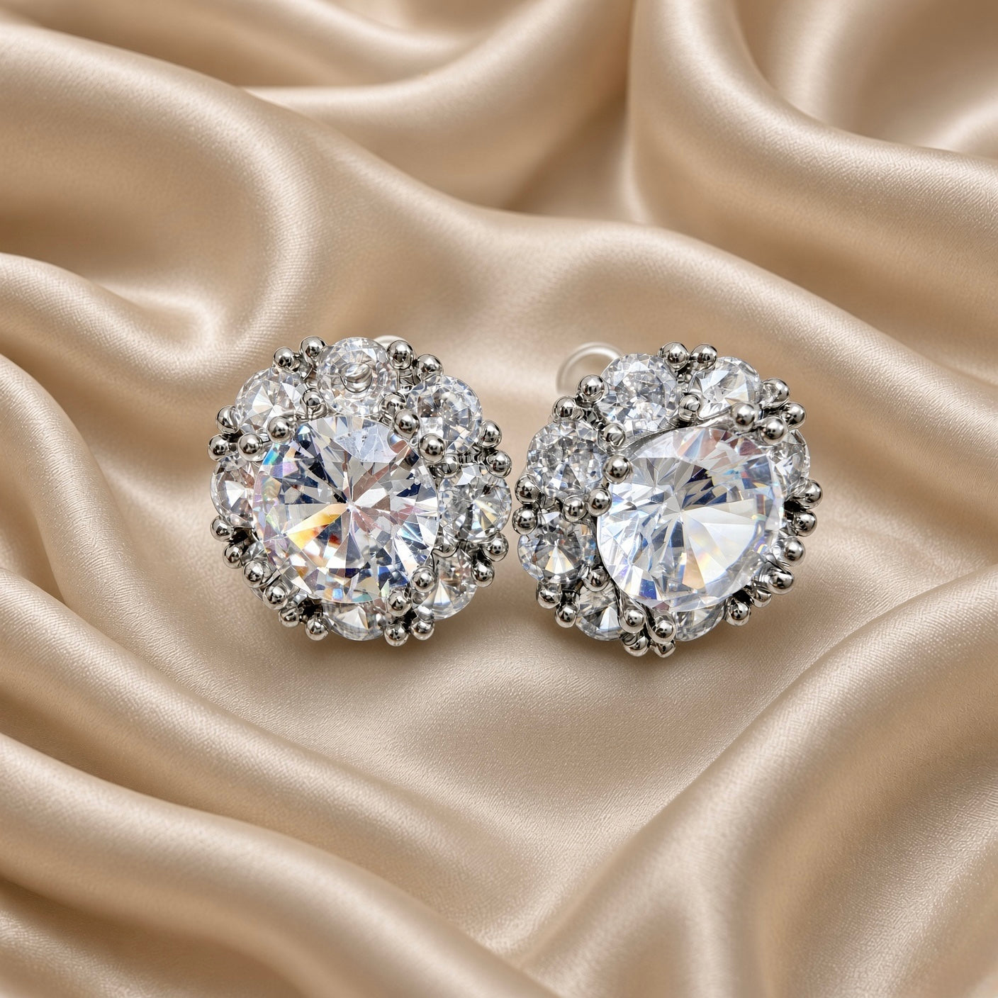 Silver floral halo stud earrings with round cubic zirconia centre stone on beige satin background