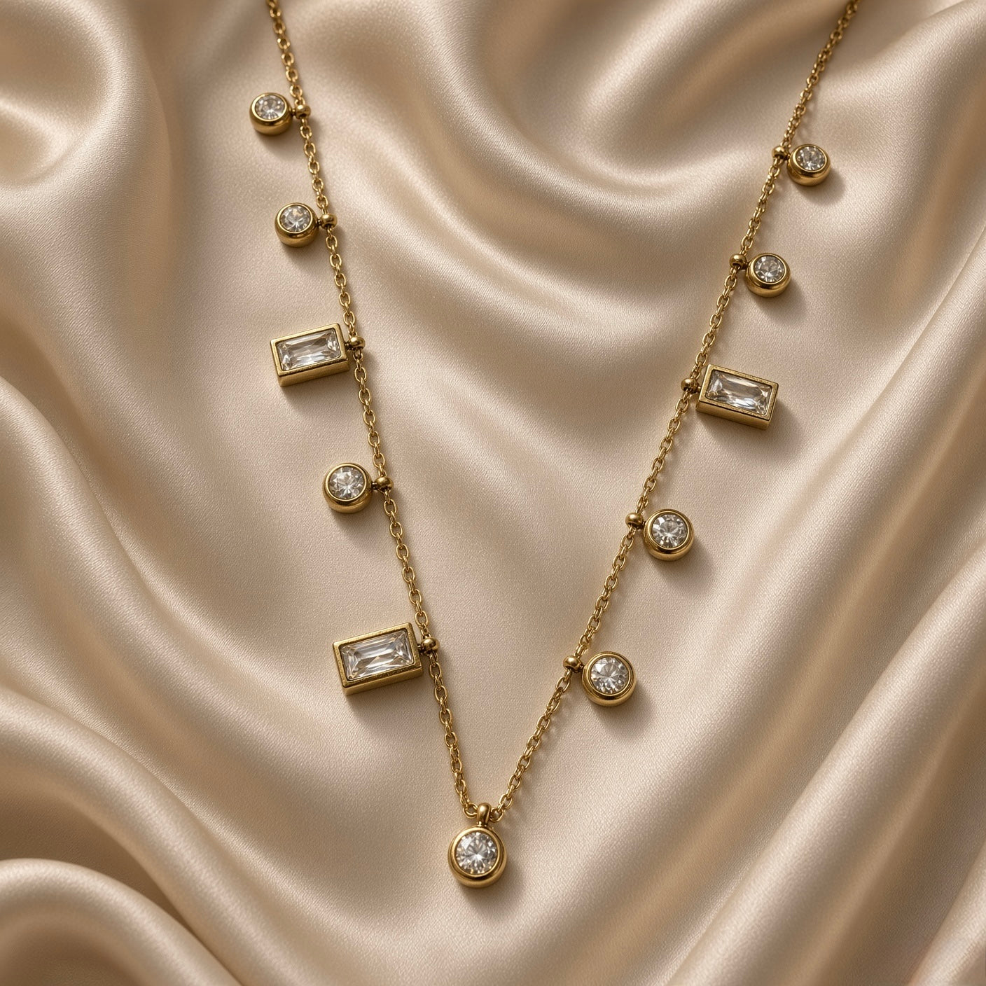 Close-up of gold-tone necklace with alternating round and rectangular crystal-style drops