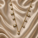 Close-up of gold-tone necklace with alternating round and rectangular crystal-style drops