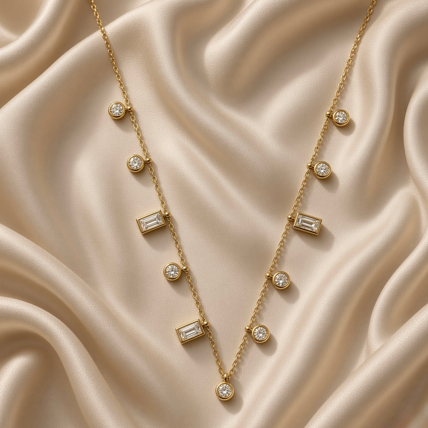 Gold-tone fine chain necklace with clear round and rectangular stone stations on satin