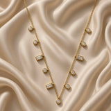 Gold-tone fine chain necklace with clear round and rectangular stone stations on satin