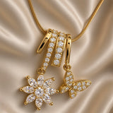 Full view of gold-tone chain necklace with flower and butterfly drop pendant on cream satin